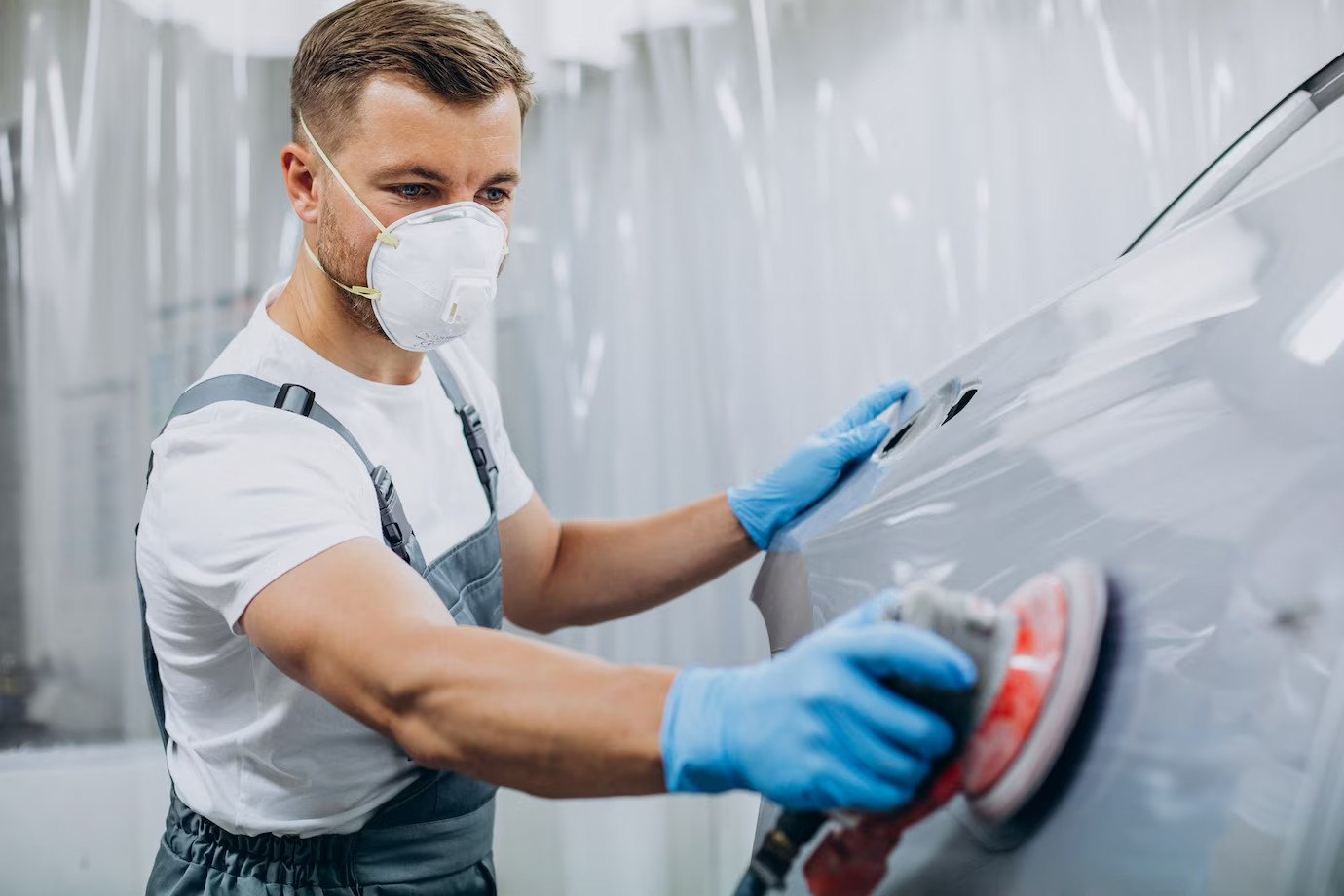 Técnico profesional arreglando la chapa y la pintura de un vehículo dentro de un taller